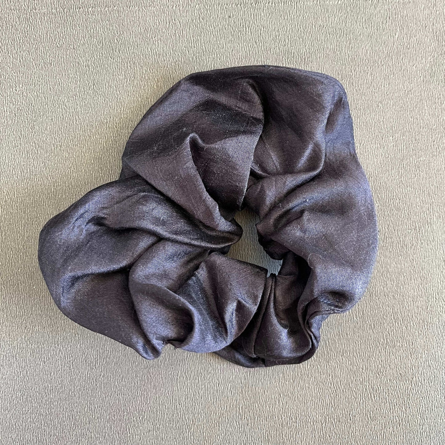 A rich, black silk-inspired scrunchie, perfect for elegant or formal looks