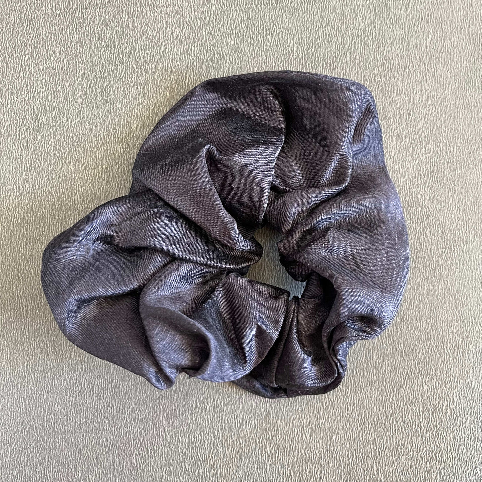 A rich, black silk-inspired scrunchie, perfect for elegant or formal looks