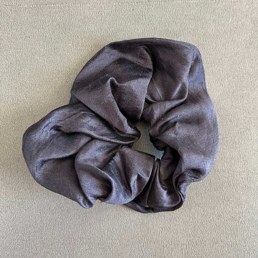 A rich, black silk-inspired scrunchie, perfect for elegant or formal looks