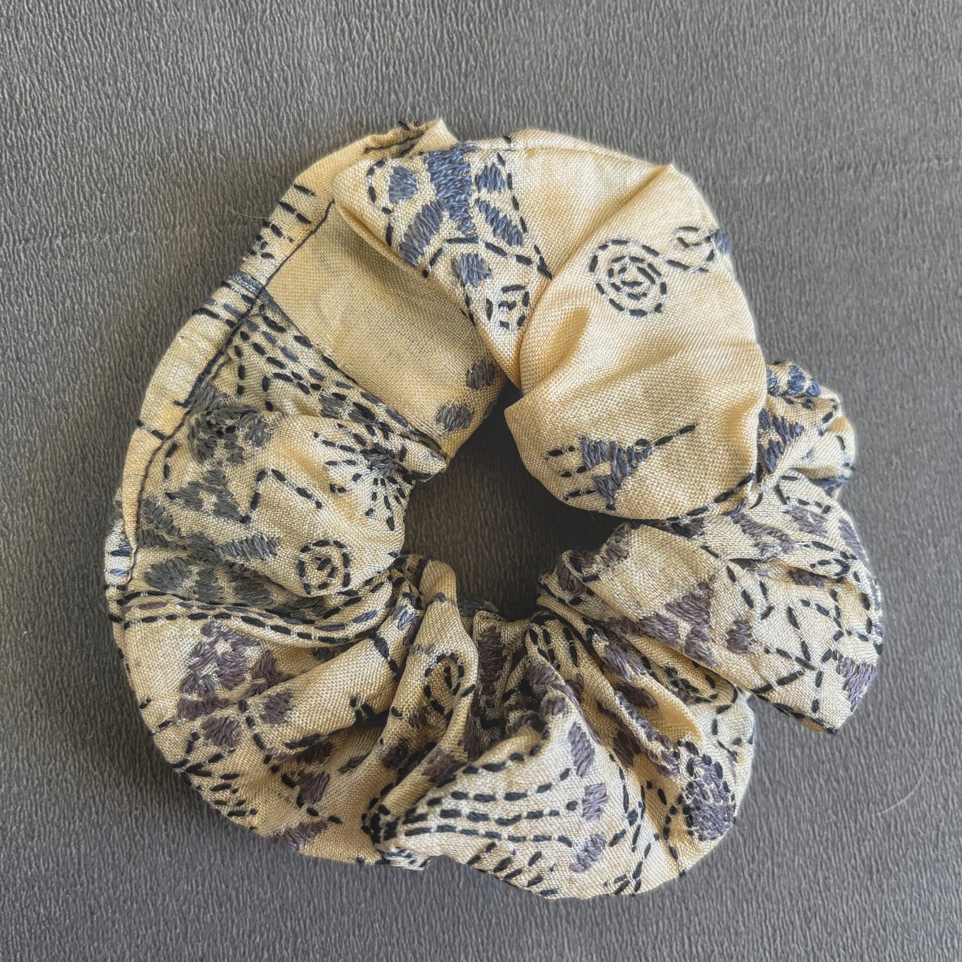 A soft yellow scrunchie patterned with small red/orange geometric accents, perfect for sunny days