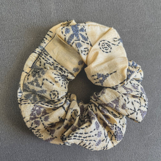 A soft yellow scrunchie patterned with small red/orange geometric accents, perfect for sunny days