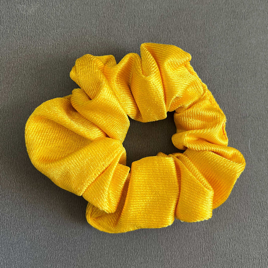 A shiny, bold yellow satin scrunchie, radiant and eye-catching.