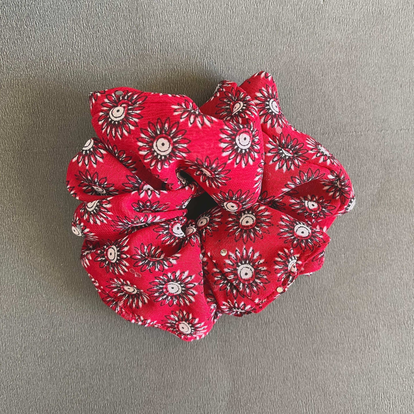 Bright red fabric covered with a playful white-and-black daisy pattern for a fun, cheerful style.